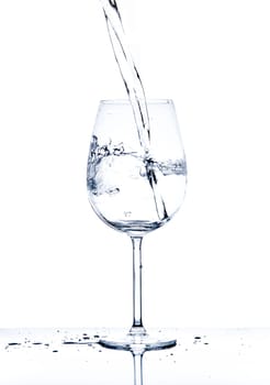Glass with the stream of dinking water on white background