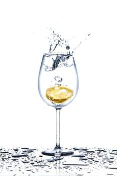 Lemon splashing into glass full of water on white background
