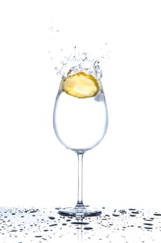 Lemon splashing into glass full of water on white background