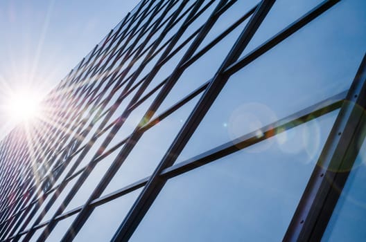 Glass and steel - mirrored facade of modern office building with sunbeams glare reflection