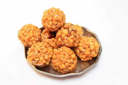 Stainless steel plate containing delicious, sweet laddoos isolated on white background