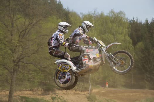 MOHELNICE, CZECH REPUBLIC - APRIL 19. Two racers in black and white are jumping a sidecar in the "International Championship of Czech Republic 2014"" on April 19. 2014  in the town of Mohelnice, Czech Republic."