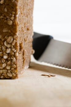 Still life with wholemeal bread and bread knife on cutting board against a bright background