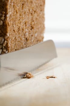 Still life with wholemeal bread and bread knife on cutting board against a bright background