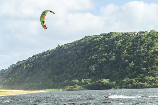Kite surfing sport action in river lagoon waters and surf action Umdloti river lagoon north of Durban South Africa.