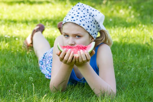 cute little girl eating watermelon on the grass
