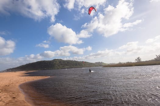 Kite surfing sport action in river lagoon waters and surf action Umdloti river lagoon north of Durban South Africa.
