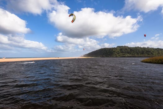 Kite surfing sport action in river lagoon waters and surf action Umdloti river lagoon north of Durban South Africa.