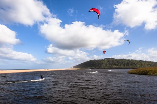 Kite surfing sport action in river lagoon waters and surf action Umdloti river lagoon north of Durban South Africa.