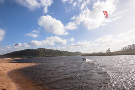 Kite surfing sport action in river lagoon waters and surf action Umdloti river lagoon north of Durban South Africa.