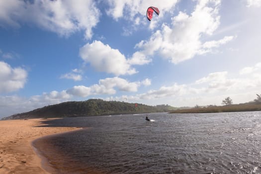 Kite surfing sport action in river lagoon waters and surf action Umdloti river lagoon north of Durban South Africa.