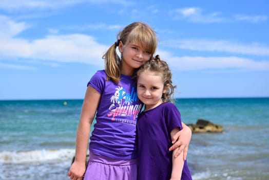 Two little sisters posing on the beach on a nice summer day, Costa Blanca, Spain