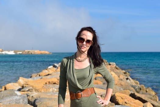Young woman posing on a rocky beach in a beautiful summer evening, Costa Blanca, Spain