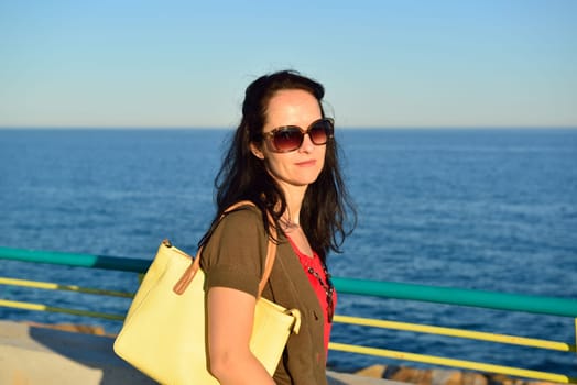 Happy young woman walking on the beach promenade on a beautiful summer evening, Costa Blanca, Spain