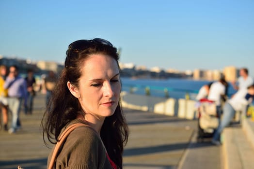 Happy young woman walking on the beach promenade on a beautiful summer evening, Costa Blanca, Spain