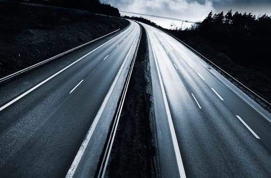 large dramatic highway, motorway at sunset, clouds, trees and forest