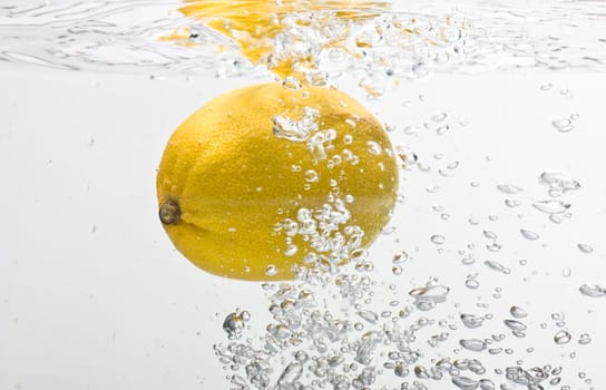 Bubbles forming in blue water after lemon is dropped into it