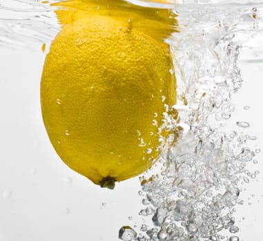 Bubbles forming in blue water after lemon is dropped into it