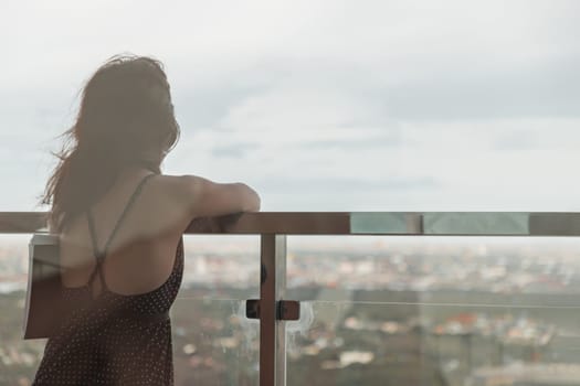 Bangkok, Thailand - Jul 19, 2020 : Young women standing resting and looking through at cityscape with skyscrapers in balcony view with clear sky before sunset. Moments of joy and relaxation atmosphere. Copy space.
