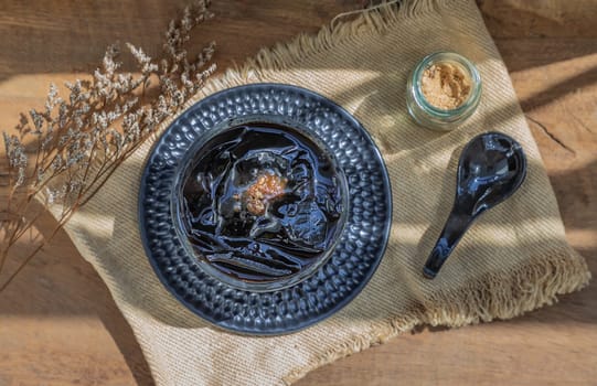 Black grass jelly (Mesona chinensis) Dessert herbal gelatin or jelly black with ice and brown sugar on the wooden background. Sweet delicious dessert chinese style.