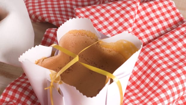 Portuguese sponge cake wrapped in the typical paper used on the baking, on wooden background.