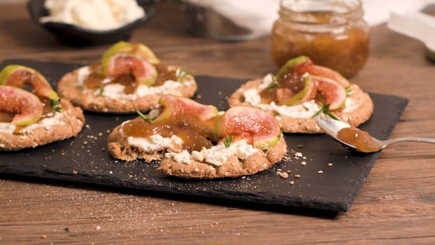 Canape or crostini with multigrain  crispread with cream cheese and fig jam on a slate board. Delicious appetizer ideal as an aperitif.