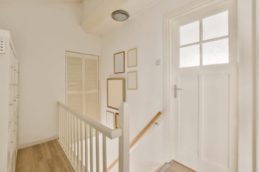 a room with white walls and wood flooring, there is a staircase leading up to the second floor on the right handrail