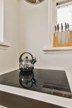 a tea kettle sitting on top of a stove in a kitchen with white walls and wood trim around the edges