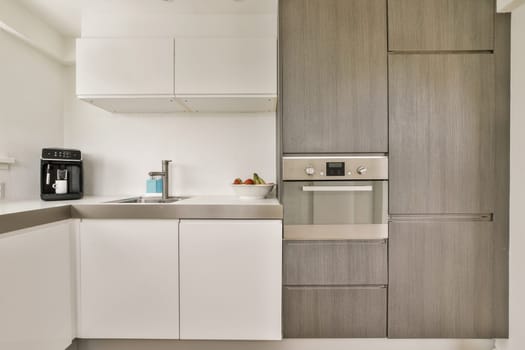 a kitchen area with white cabinets and gray countertops on either side, one has a coffee machine in the corner