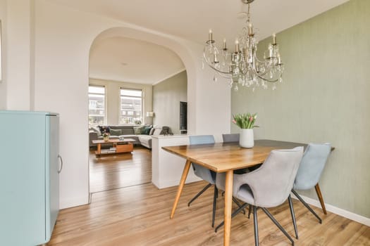 a dining room with wood flooring and light green wallpaper in the room is decorated with chandels