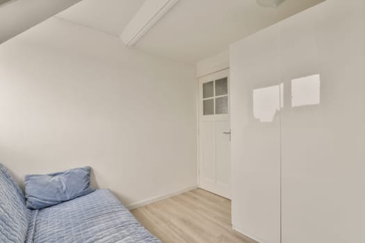 a bedroom with white walls and light wood flooring in the middle of the room, there is a bed on the right side