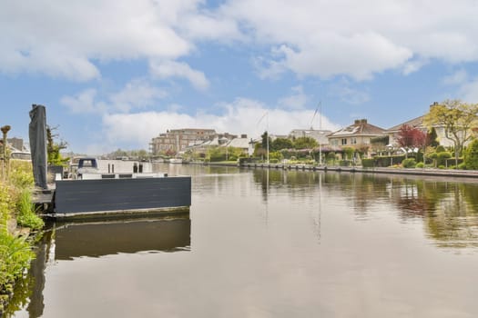 a boat in the water with houses and buildings in the background on a cloudy day, as seen from across the canal