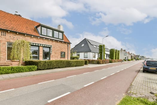 some houses on the side of a road with cars parked in front of them and one car driving down the street