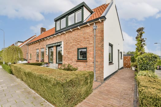 a house in the netherlands with red brick walls and green shutters on either side, there is a driveway leading up to the