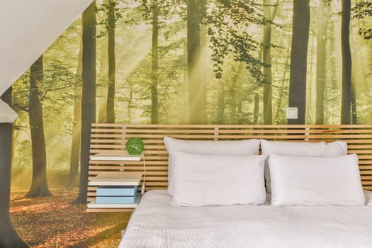 a bed in a bedroom with trees on the wall behind it and a book shelf next to the headboard