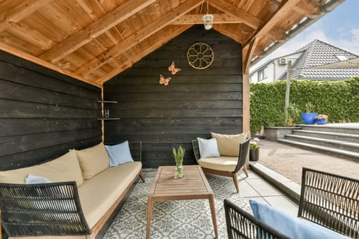 an outdoor living area with couches, tables and umbrellas on the outside patio in front of a house