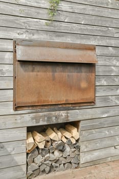 an old mailbox on the side of a building with firewood stacked up in it's front door