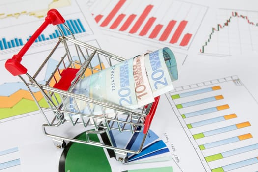 Shopping cart with money on the business charts