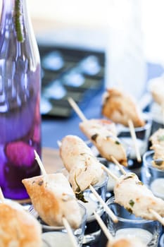 Closeup of pieces of cooked chicken on wooden skewers with mayonnaise based condiment in small glasses