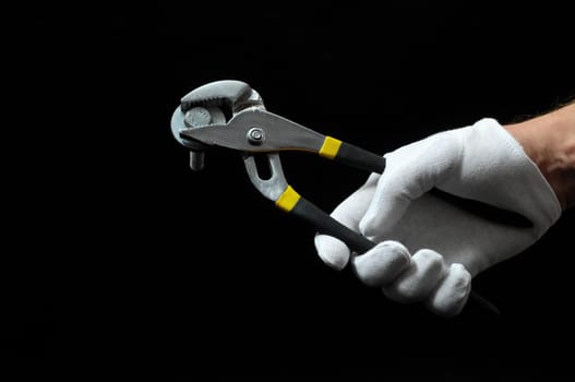 Pliers and a Hand on a Black Background