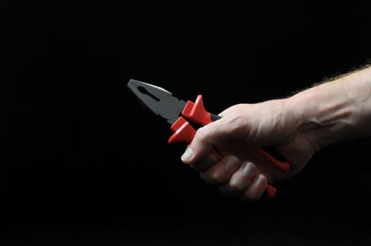 Pliers and a Hand on a Black Background