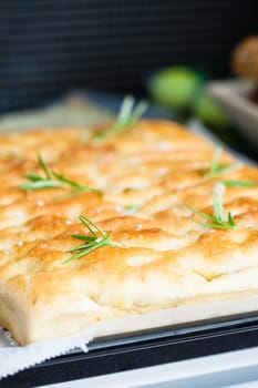 Closeup of freshly baked focaccia bread on black granite stone serving tray