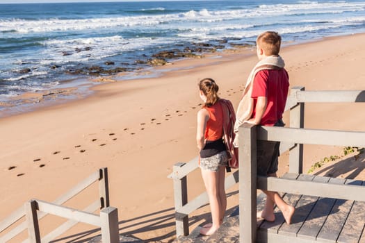 Girl boy teenager on stairs arriving at ocean beach for fun sport relax