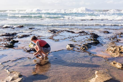 Girl teenager daughter exploring ocean beach sand rock reefs pools at low tide