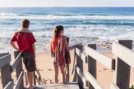 Girl boy teenager on stairs arriving at ocean beach for fun sport relax