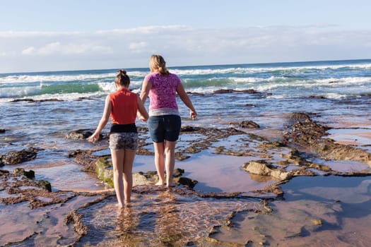 Girls mother daughter together exploring ocean beach rock reefs pools at low tide