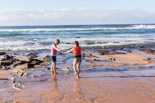 Girls mother daughter together exploring ocean beach rock reefs pools at low tide