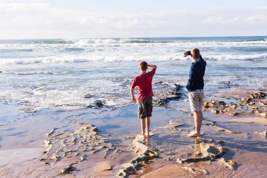 Boys teenagers family together exploring ocean beach rock reefs pools at low tide