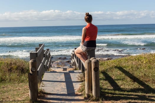 Girl teenager daughter overlooking landscape ocean beach sand rock reefs pools at low tide from stairs
