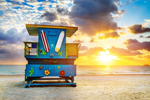 Miami South Beach sunrise with lifeguard tower and coastline with colorful cloud and blue sky.